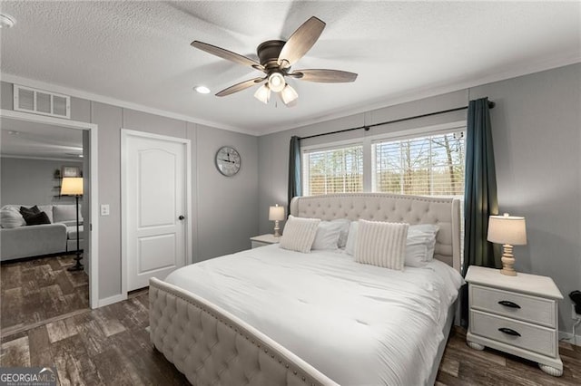 bedroom featuring visible vents, dark wood-type flooring, ornamental molding, a textured ceiling, and a ceiling fan