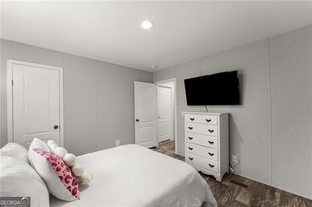 bedroom with a decorative wall, recessed lighting, and wood finished floors