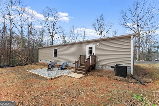rear view of property featuring crawl space, a fire pit, and central AC unit