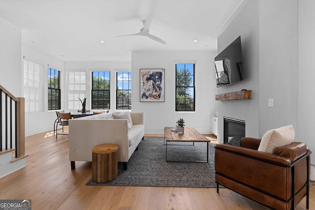 living area with hardwood / wood-style floors, baseboards, a glass covered fireplace, and recessed lighting