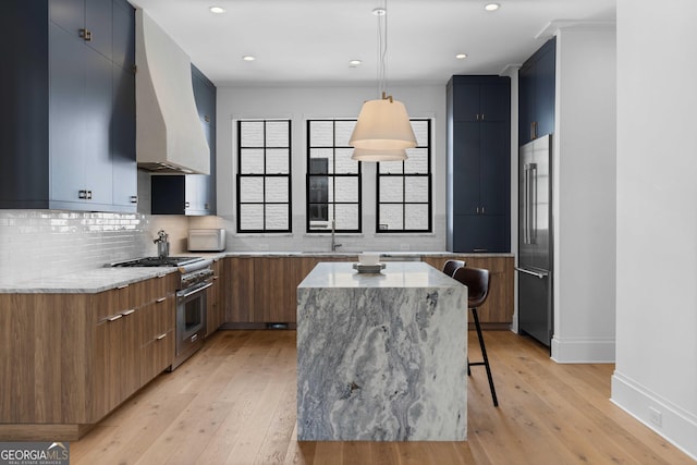 kitchen featuring premium range hood, light wood finished floors, a kitchen island, high quality appliances, and modern cabinets