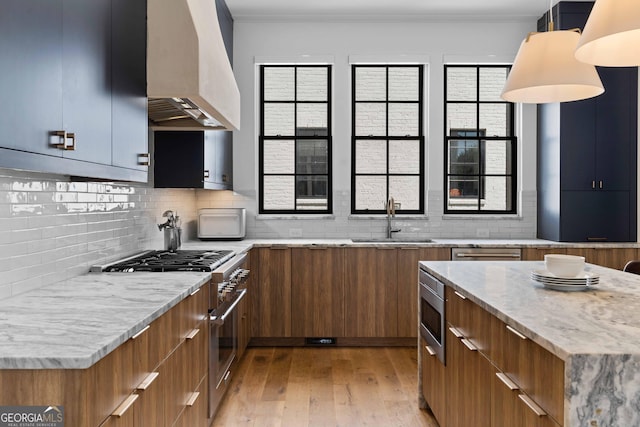 kitchen with modern cabinets, a sink, stainless steel appliances, brown cabinetry, and custom exhaust hood