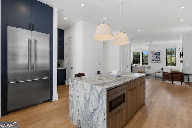 kitchen with recessed lighting, built in appliances, light stone countertops, and light wood finished floors