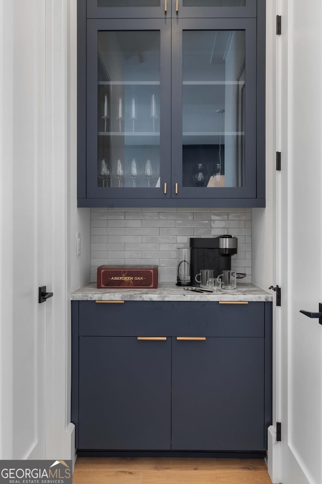 bar with decorative backsplash and light wood-type flooring