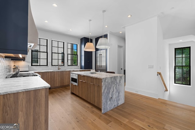 kitchen with a center island, light wood-type flooring, brown cabinets, modern cabinets, and a sink