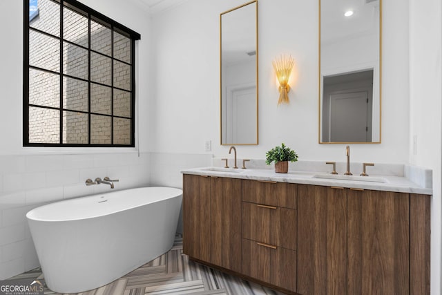 bathroom featuring double vanity, a freestanding tub, and a sink