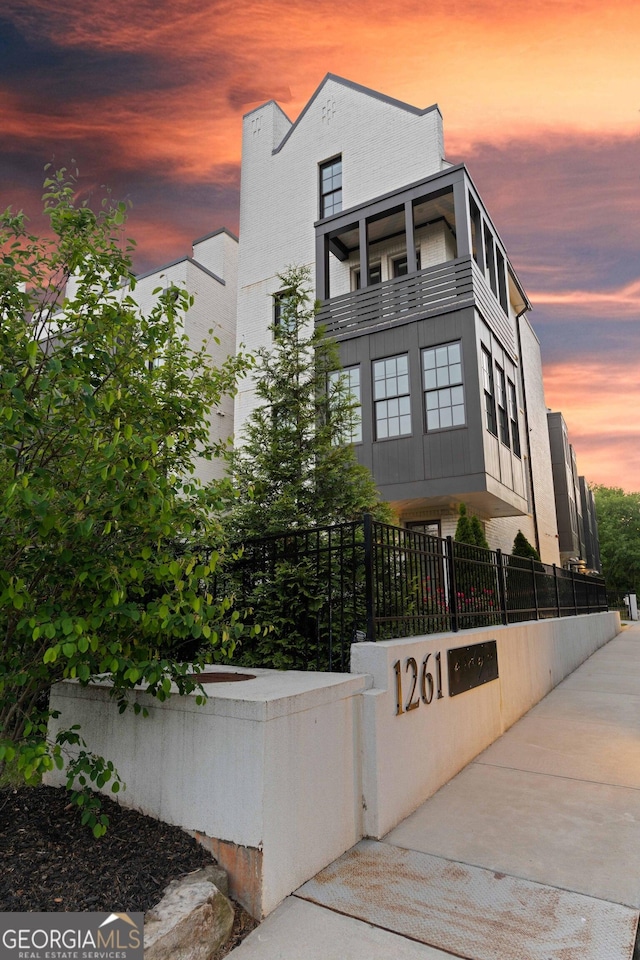 modern home featuring a fenced front yard and a balcony