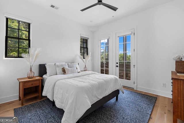 bedroom featuring access to outside, multiple windows, wood finished floors, and visible vents