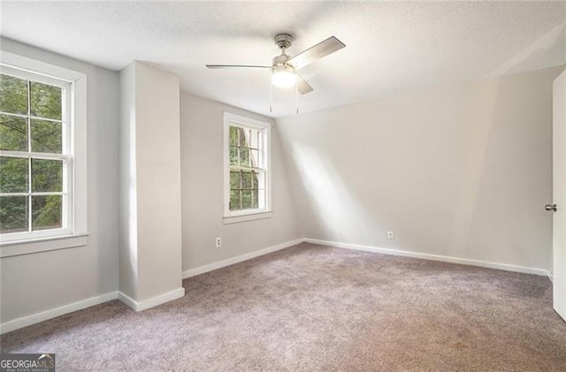 carpeted spare room featuring a textured ceiling, baseboards, and a ceiling fan