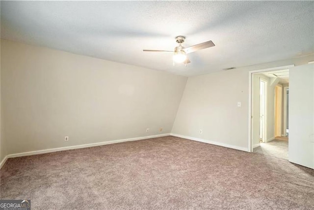 spare room featuring a textured ceiling, carpet flooring, visible vents, and ceiling fan