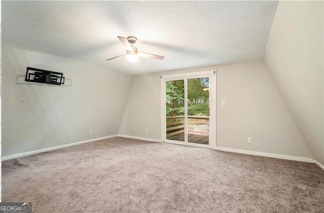 empty room featuring baseboards, lofted ceiling, ceiling fan, a textured ceiling, and carpet flooring