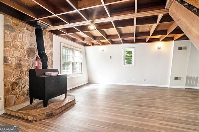 unfurnished living room featuring visible vents, a healthy amount of sunlight, and a wood stove