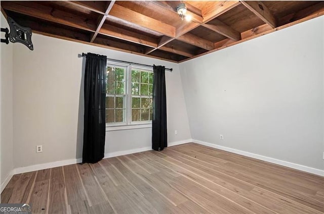 spare room featuring beam ceiling, wood finished floors, baseboards, and coffered ceiling