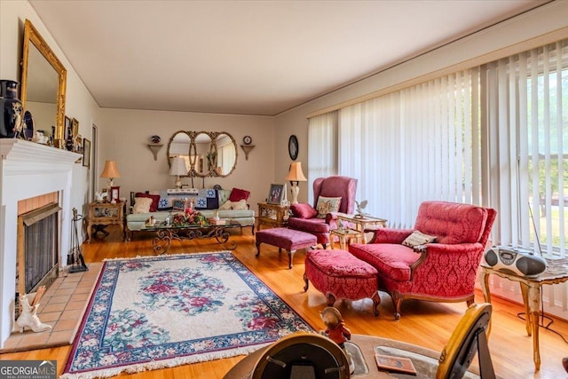 living area featuring a healthy amount of sunlight, wood finished floors, and a tile fireplace