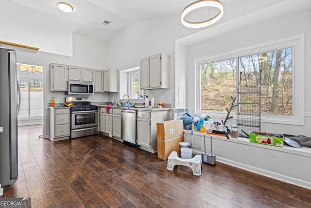 kitchen with dark wood finished floors, light countertops, vaulted ceiling, stainless steel appliances, and a sink