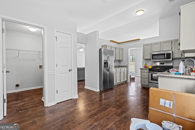 kitchen featuring dark wood-style floors, appliances with stainless steel finishes, baseboards, and gray cabinetry