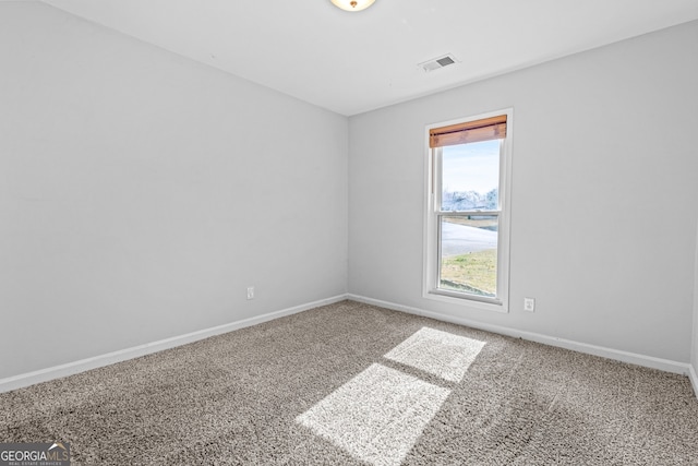 spare room featuring carpet flooring, baseboards, and visible vents