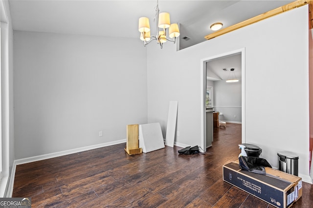 empty room featuring baseboards, an inviting chandelier, and wood-type flooring