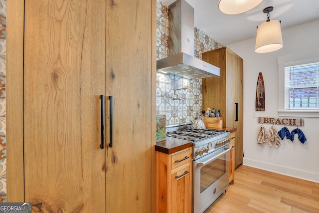 kitchen with light wood-type flooring, island exhaust hood, tasteful backsplash, stainless steel stove, and baseboards