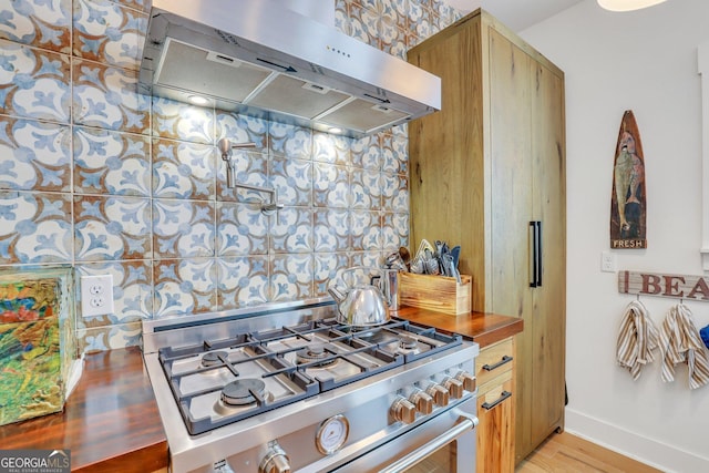 kitchen with under cabinet range hood, gas range, light wood-type flooring, and baseboards