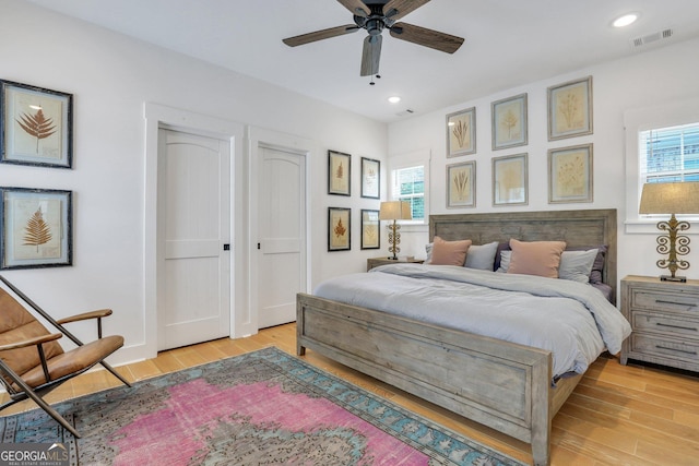 bedroom with multiple windows, light wood-style floors, and visible vents