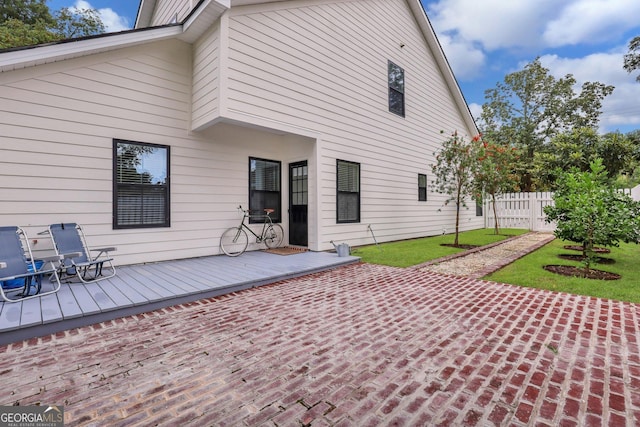 rear view of house with a wooden deck, a yard, and fence