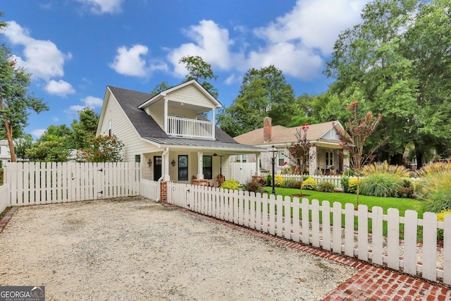 view of front facade with a fenced front yard, covered porch, a balcony, driveway, and a gate