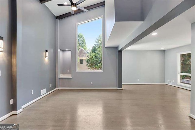 unfurnished living room featuring baseboards, wood finished floors, plenty of natural light, and ceiling fan