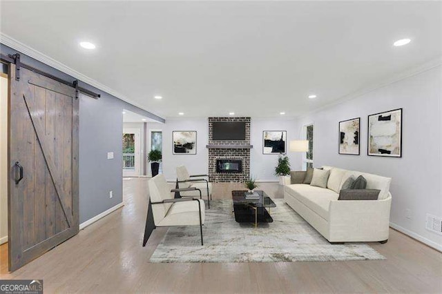 living room featuring a fireplace, a barn door, wood finished floors, and recessed lighting