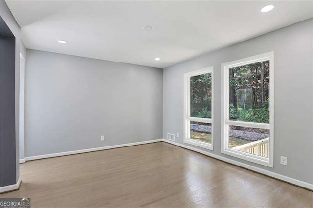 empty room with recessed lighting, wood finished floors, and baseboards