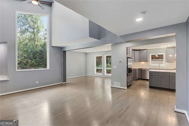 unfurnished living room with baseboards, wood finished floors, and a ceiling fan