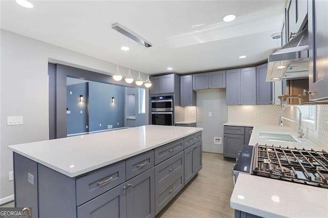 kitchen featuring gray cabinetry, a sink, a kitchen island, stainless steel double oven, and decorative backsplash