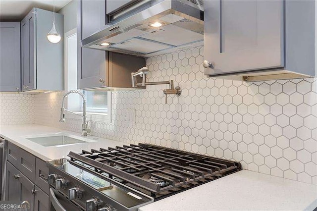 kitchen with under cabinet range hood, backsplash, light countertops, and a sink