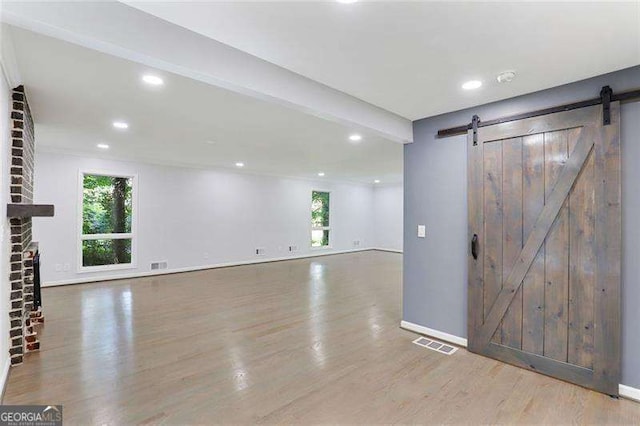 interior space featuring a barn door, wood finished floors, and visible vents