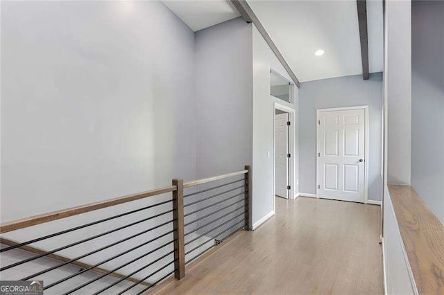 corridor with baseboards, an upstairs landing, and wood finished floors