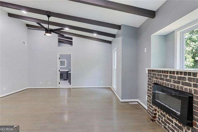 living room featuring a brick fireplace, baseboards, lofted ceiling with beams, wood finished floors, and a ceiling fan