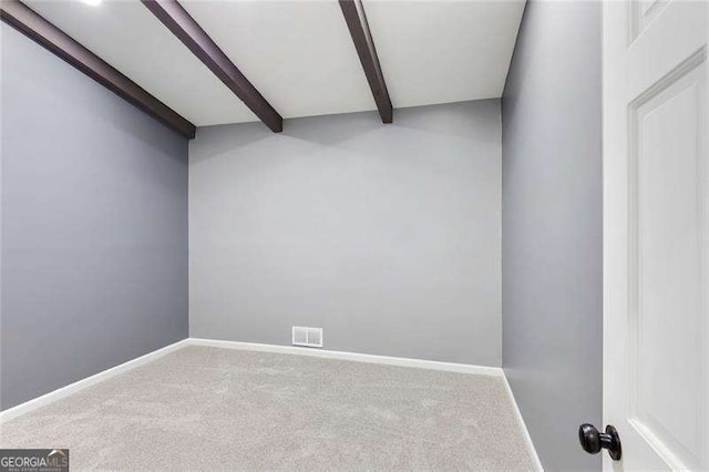 carpeted spare room with beamed ceiling, visible vents, and baseboards