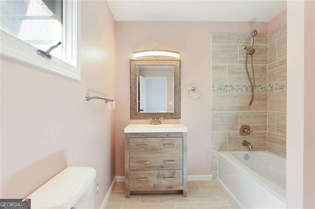 full bathroom featuring baseboards, toilet, vanity, and bathtub / shower combination