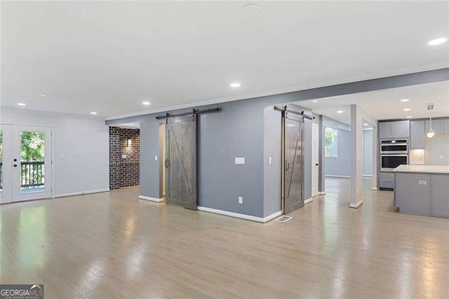 unfurnished living room with recessed lighting, a barn door, light wood-style flooring, and crown molding