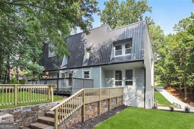 back of house featuring a deck, a yard, a gambrel roof, and metal roof