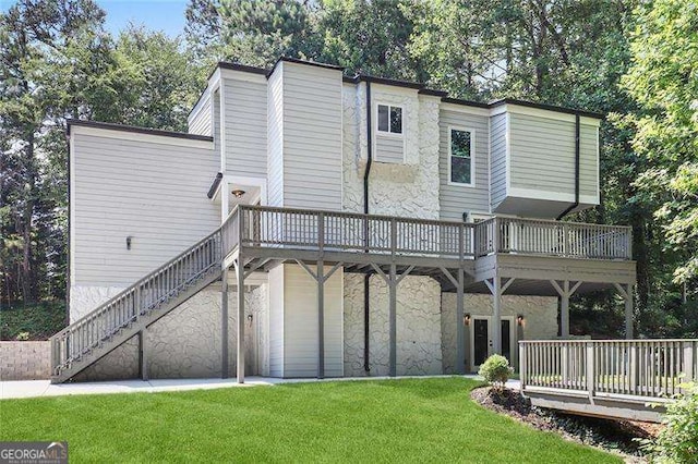 rear view of house with stone siding, a lawn, a wooden deck, and stairs