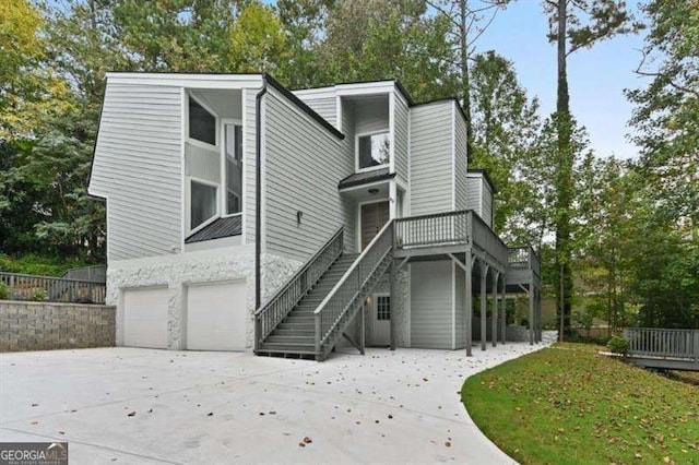 view of front facade featuring a garage, concrete driveway, and stairs