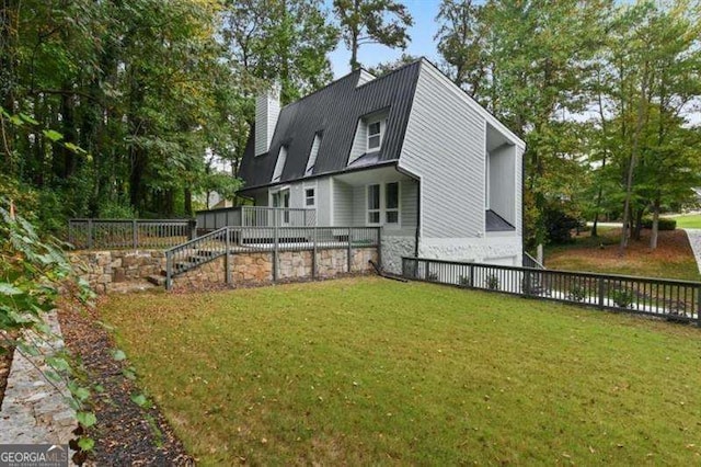 rear view of house featuring stairs, a lawn, and a chimney