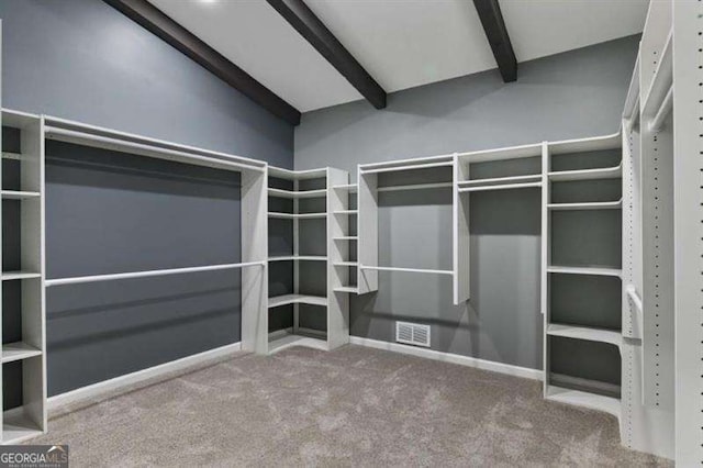 spacious closet featuring beam ceiling and carpet flooring