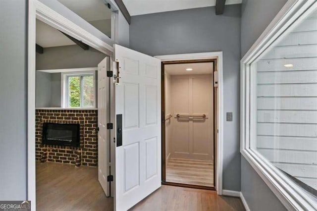 interior space with baseboards, beam ceiling, and wood finished floors