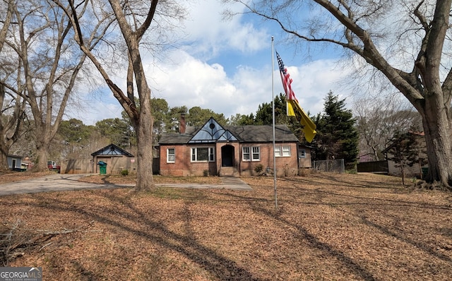 view of front of property with brick siding, a chimney, and fence