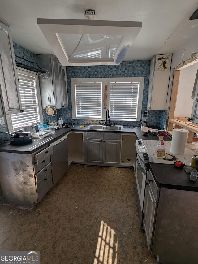 kitchen with dark countertops, a sink, electric range, and stainless steel dishwasher