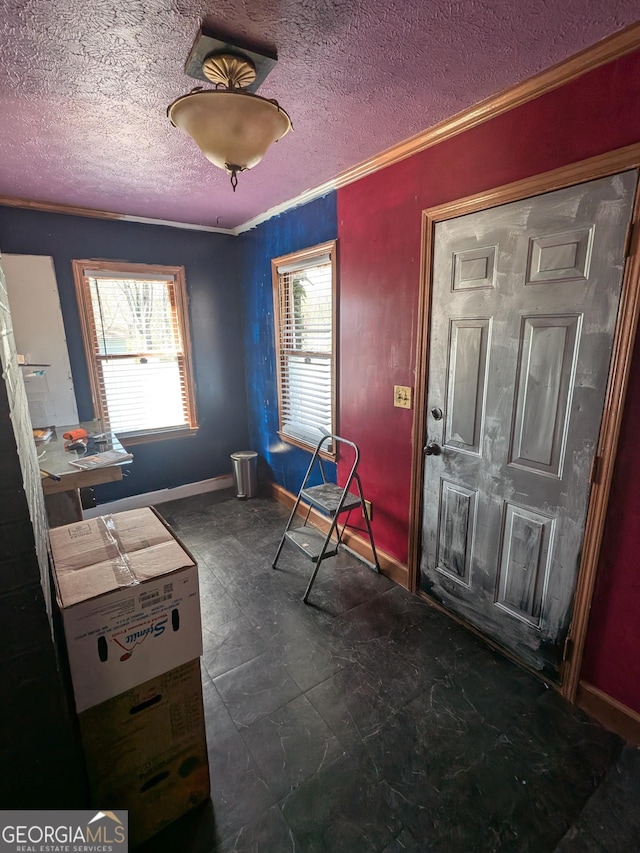 interior space featuring plenty of natural light, a textured ceiling, crown molding, and baseboards