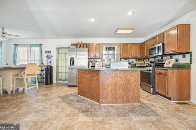 kitchen with a textured ceiling, a healthy amount of sunlight, and appliances with stainless steel finishes