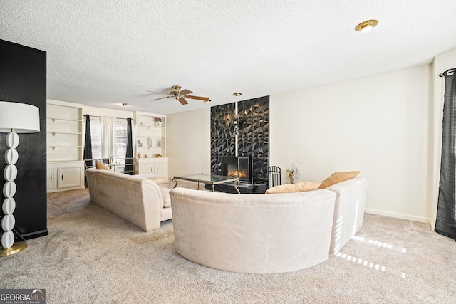 living area featuring built in features, a textured ceiling, carpet floors, baseboards, and ceiling fan